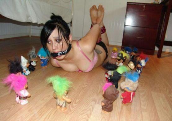 Photo d'une jeune femme nue attachée entourée de poupée de trolls