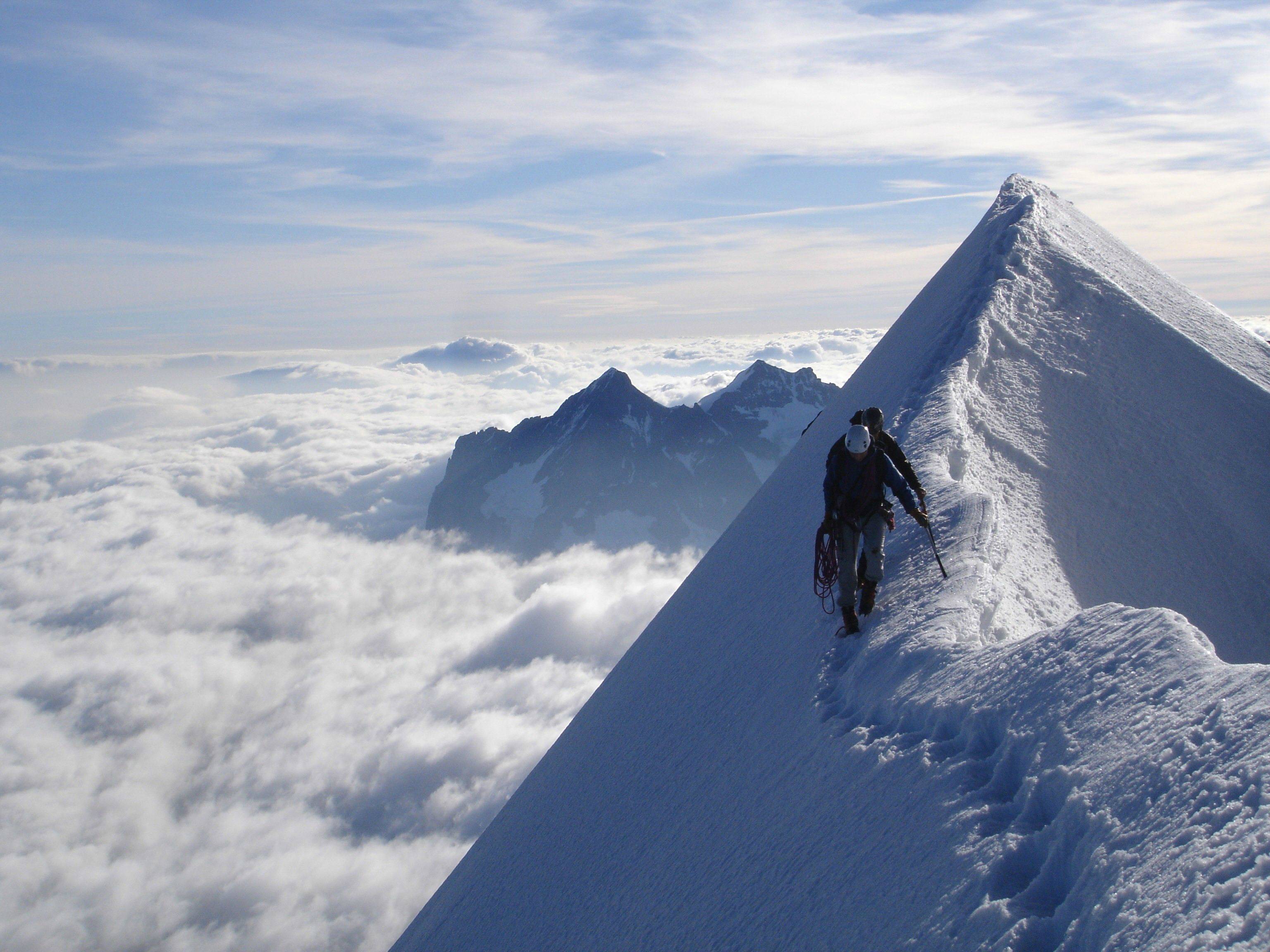 Photo d'un homme qui grimpe un sommet enneigé.