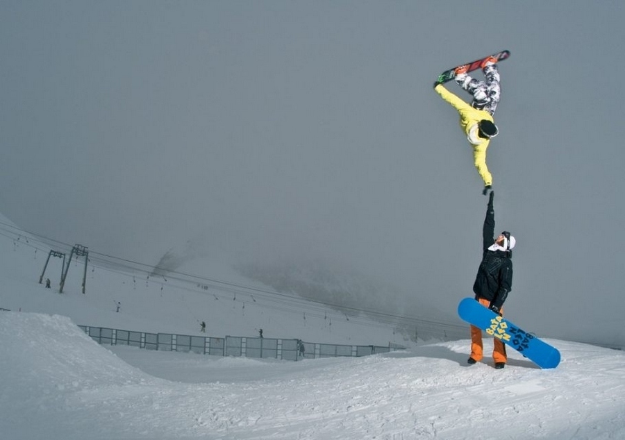 Photo d'un saut de snowboarder touchant un autre de sa main