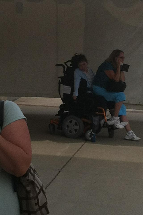 Photo d'une grosse femme téléphonant assise sur un homme en chaise roulante